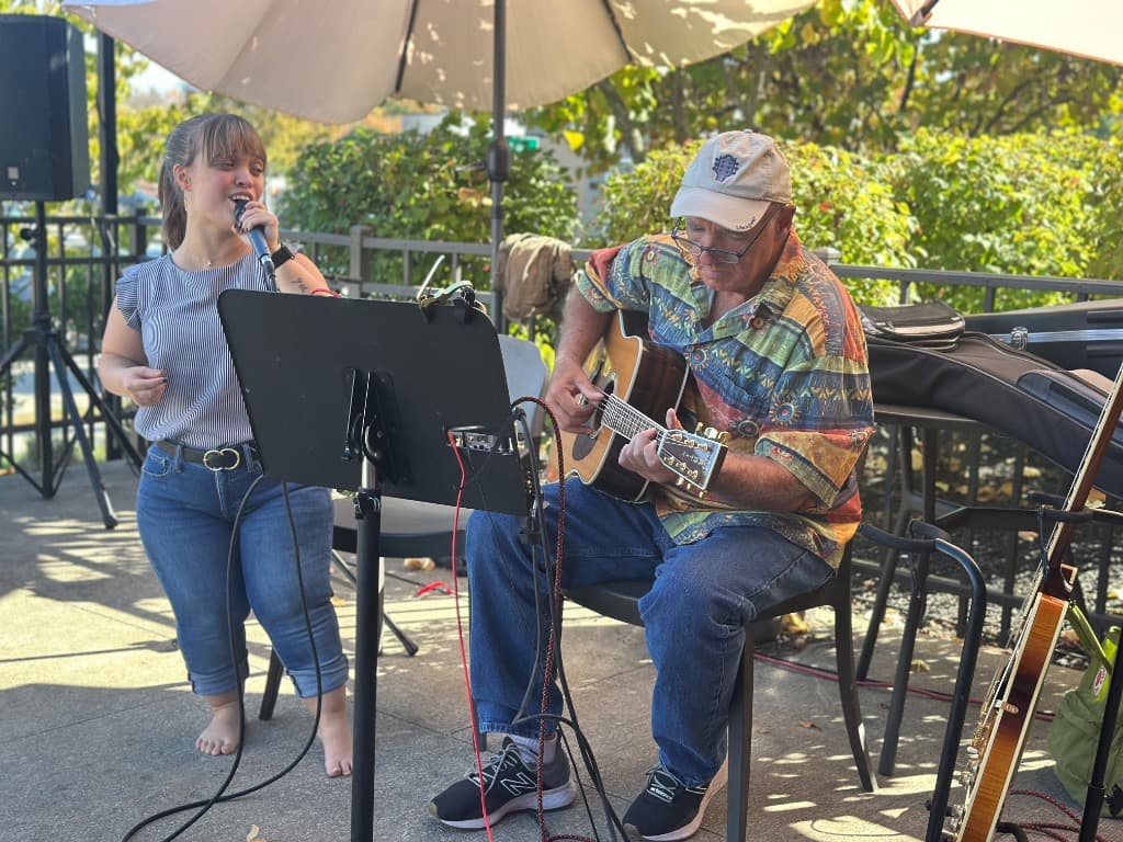 Zach and Lyndsey playing live acoustic music on an outdoor garden patio in Massachusetts